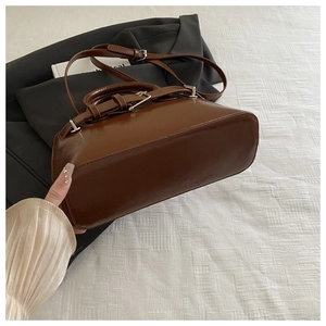 Detail view of the brown leather bag base with silver buckles and adjustable strap