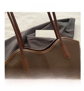 Close-up of brown litchi grain leather tote bag with fashion label and slim shoulder straps