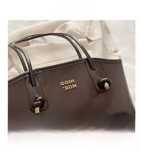 Detail of dark brown leather handbag with knotted handle and gold metal COIH 2DN logo