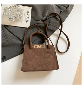 Detail of dark brown frosted suede handbag with golden metal twist-lock and top handle