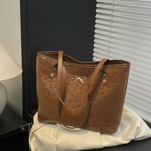 Brown leopard print tote bag with gold bow detail and rivets on white fabric