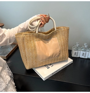 Detail of woven straw tote bag with leather patch and thick white cotton rope handles