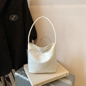 Sac à main minimaliste en cuir blanc avec lettrage and future posé sur une valise