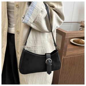 Detail of black crescent shoulder bag with silver buckle worn over a beige trench coat