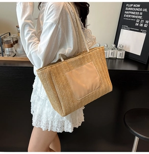Detail of woven straw tote bag featuring a leather pocket held by a model in a cafe