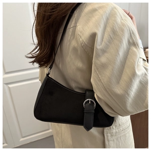 Detailed view of black leather shoulder bag with silver buckle worn by a model