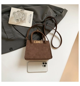 Detail of vintage brown matte suede handbag with golden turn-lock and rounded handle