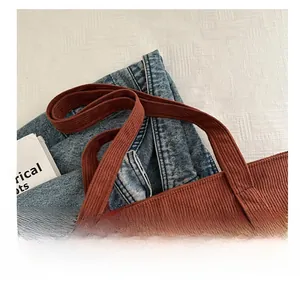 Detailed view of brown corduroy tote bag handle with high-quality stitching texture