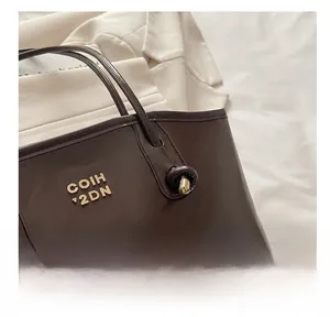 Detailed close-up of dark brown leather tote bag showing metallic logo and knot handle