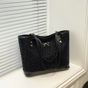 Fashionable leopard print large tote bag with golden bow and leather handles on white table