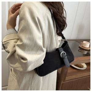 Detailed view of black suede crescent bag with silver metal buckle on a model