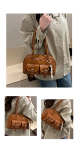 Dettaglio di una borsa Boston marrone lucida con tasche frontali e ciondolo a perle