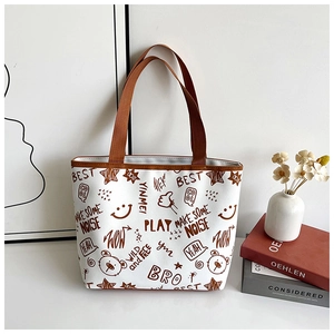 Detailed close-up of white canvas tote bag with brown bear graffiti and wide shoulder strap