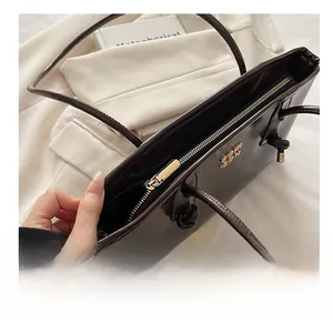 Detail view of smooth metal zipper and gold logo on the dark leather tote bag