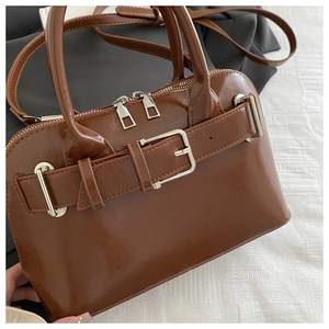 Macro shot of brown faux leather bag with silver buckle and glossy finish detail