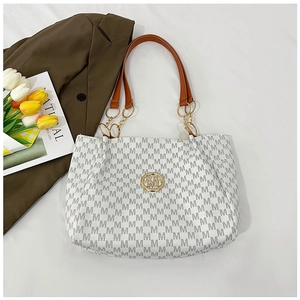 Close-up of white tote bag with M-pattern print and large gold metal logo detail