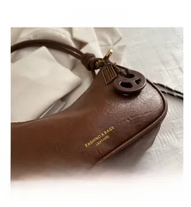 Detailed macro view of the brown glossy vintage leather bag with gold logo and charm