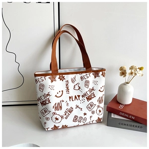 Close-up of canvas tote bag featuring brown graffiti bear prints and woven handles