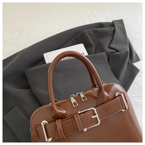 Close-up of vintage brown leather tote bag with silver buckle and metallic zippers