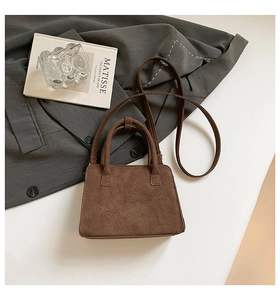 Detail of dark brown matte suede handbag with dual top handles and adjustable shoulder strap