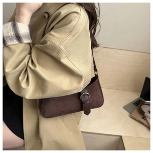 Detailed view of vintage dark brown suede shoulder bag worn with a khaki trench coat