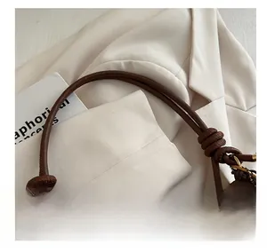 Close-up of brown leather bag shoulder strap with unique ring knot and gold buckle detail