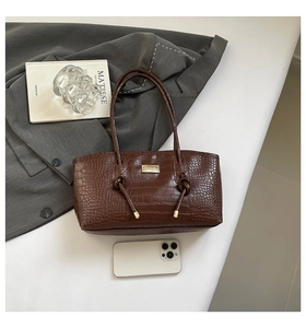 Détail du sac cabas marron embossé crocodile avec plaque dorée et poignée nouée élégante