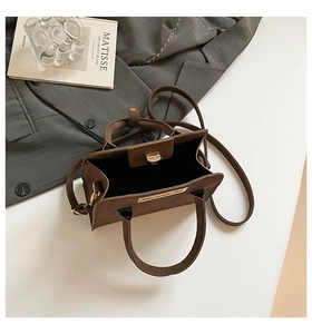 Detail of vintage matte brown handbag with metal clasp on a stylish modern tabletop