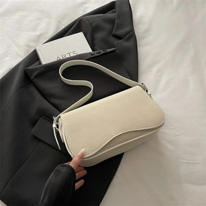 Minimalist cream white underarm bag with curved flap shown on a sleek studio backdrop