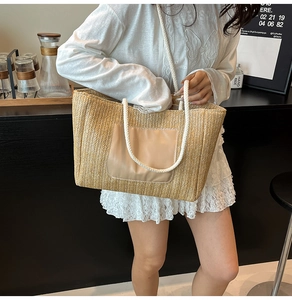 Detail of hand-woven straw tote bag with leather patch and ivory rope handles