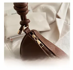 Close-up of golden zipper and knotted leather handle on brown vintage shoulder bag