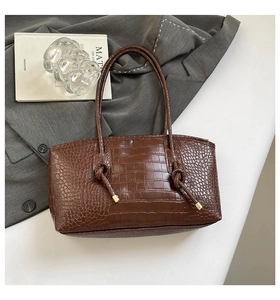 Détails de la texture crocodile marron foncé et des finitions dorées du sac cabas