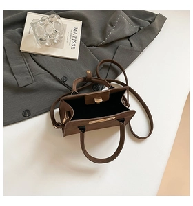 Detailed view of a dark brown matte handbag with golden lock and adjustable strap