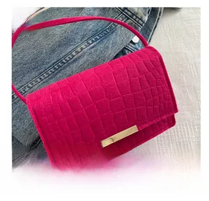 Detail of fuchsia crocodile pattern leather bag with gold metal buckle on denim background