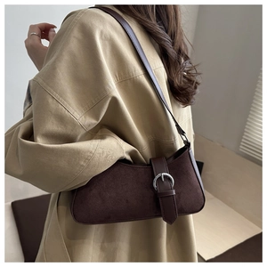 Close-up of dark brown suede shoulder bag featuring a silver ring buckle and leather strap