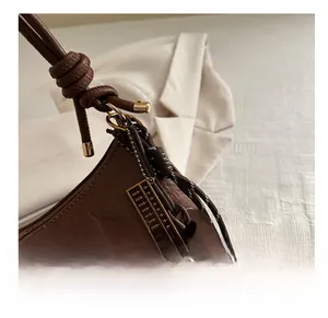 Detail of vintage brown leather bag featuring unique metal abacus pendant and woven rope