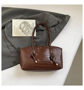 Détails de la texture crocodile marron et du nœud décoratif sur un sac fourre-tout