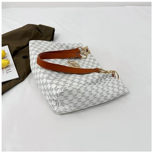Macro view of white monogram tote bag with brown leather straps and gold M charm