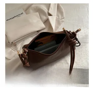 Detail view of brown leather bag interior showing phone storage and gold hardware caps