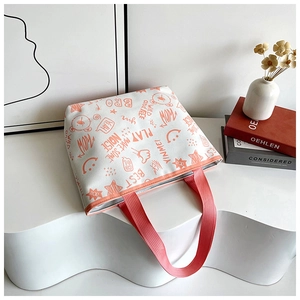 Detail of canvas tote bag featuring playful graffiti prints and pink ribbon handles