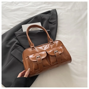 Close-up of caramel leather handbag with dual front pockets and silver buckles on a blazer