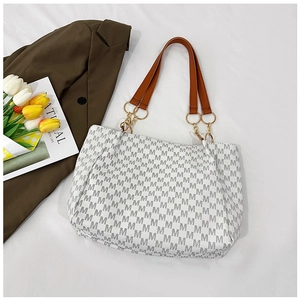 Detail view of the tote bag showing gray M-pattern print and gold chain hardware accents