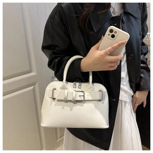 Detail of white glossy handbag with silver buckle and structured top handle in use