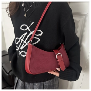 Détail du sac croissant bordeaux avec texture en daim et boucle métallique argentée