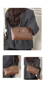 Close-up of brown glossy leather shoulder bag featuring a gold metallic logo detail