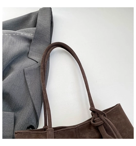 Close-up of a vintage dark brown suede tote bag with knotted handle and shoulder strap