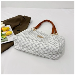 Detail of M-pattern tote bag featuring brown leather handles and golden metal rings