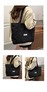 Detail view of black corduroy tote bag showing vertical texture and logo patch