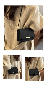 Detail view of a black crocodile-patterned crossbody bag with elegant gold metal buckle