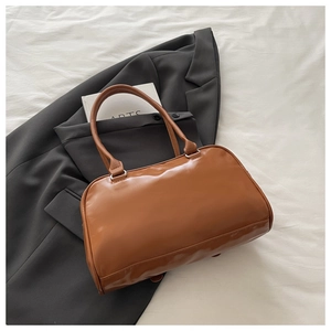Flat lay of a brown leather Boston bag with double handles on a grey blazer background